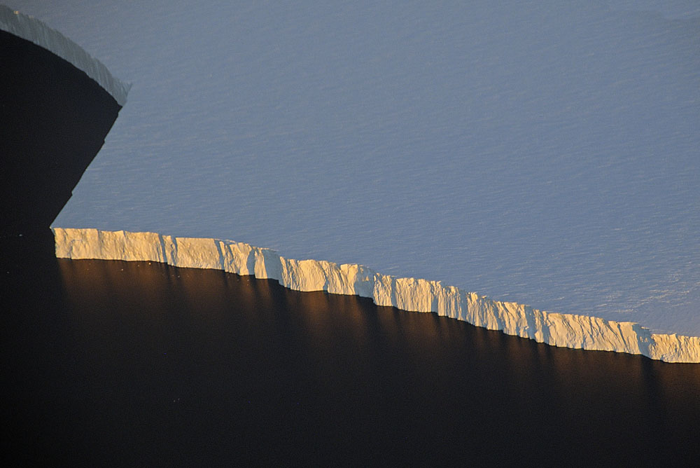 Edge of solid sheet of ice forms massive cliff at the sea