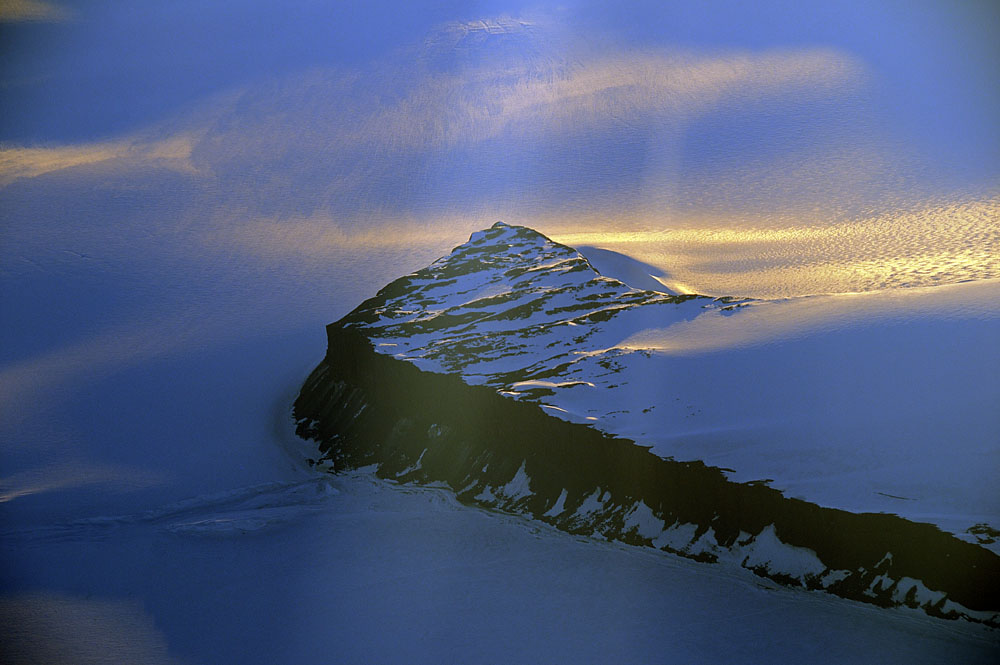 Antarctic mountain sunlit by a break in low clouds