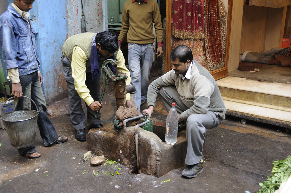 Men pumping water in Old Delhi street