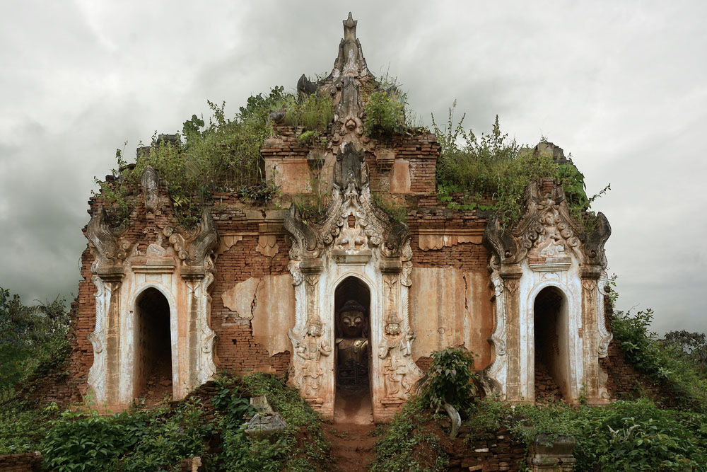 Overgrown building with Buddha inside