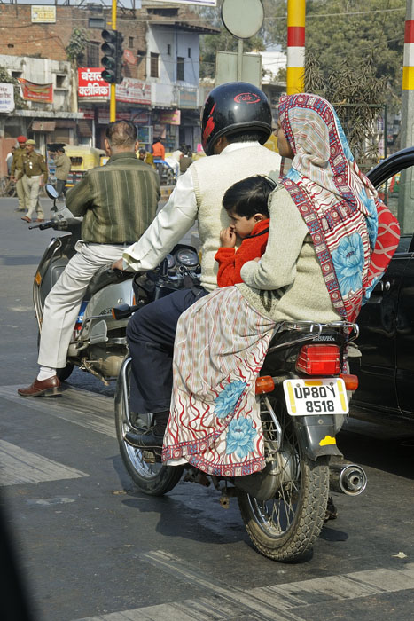 Family on scooter with soldiers in the background