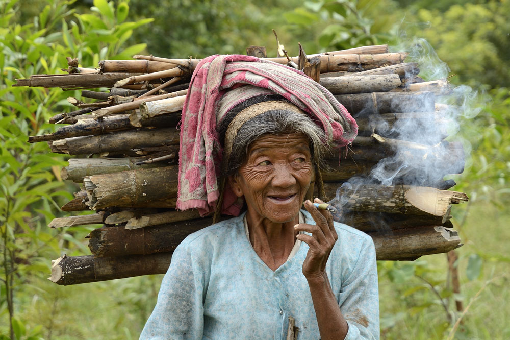 Cigar smoking old woman carrying wood